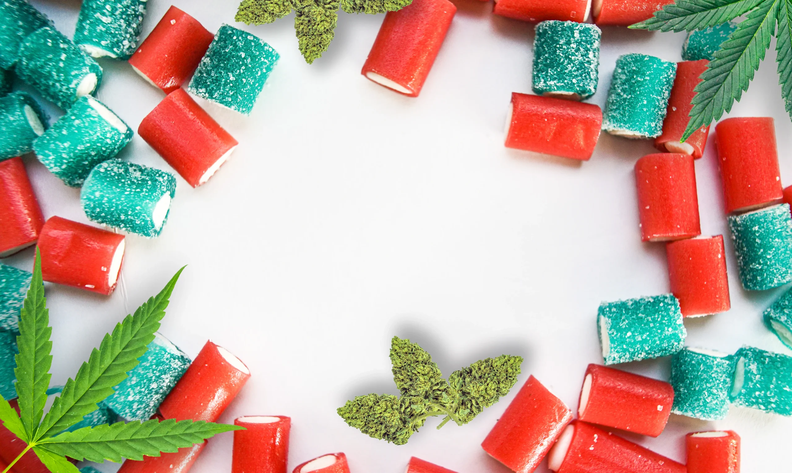 Red and blue gummy candies arranged in a circle on a white surface, with green marijuana leaves and buds placed among the candies. The setup highlights cannabis delivery NYC & Long Island, NY, with the empty center drawing attention.