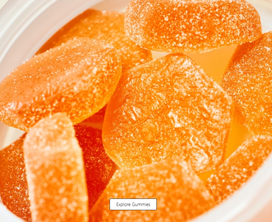 Close-up of several orange, hexagon-shaped gummies covered in sugar, inside a white container.