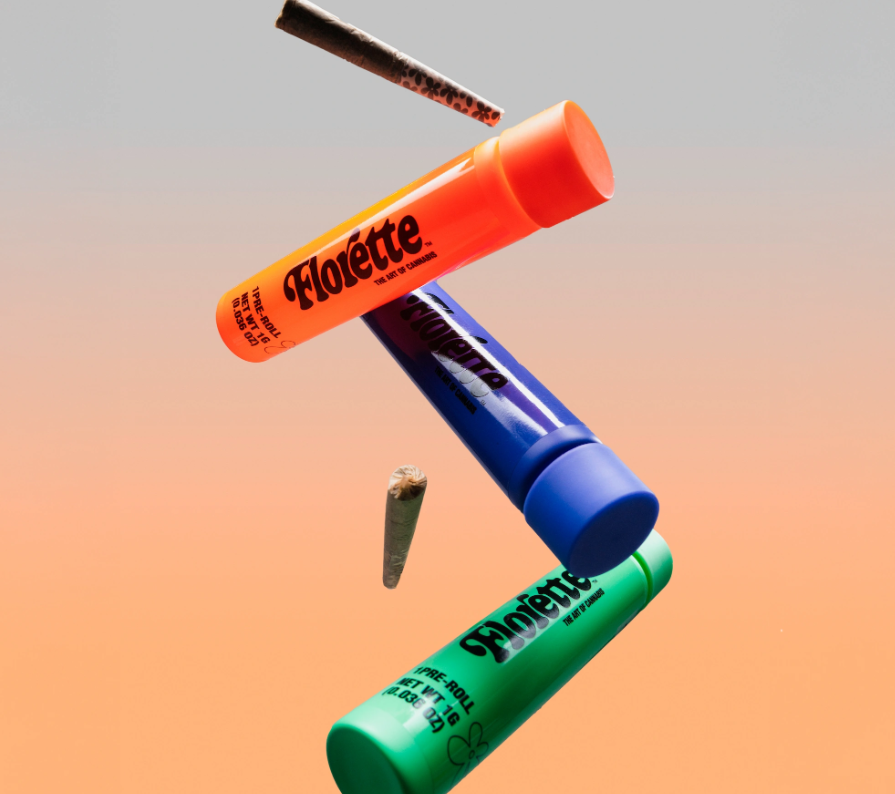 Three Florette highlighters in orange, blue, and green float diagonally alongside two rolled paper cones against a gradient gray to peach background.
