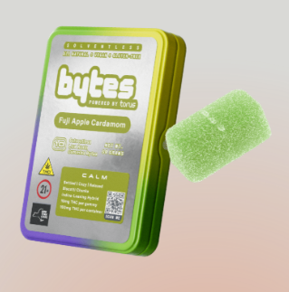 A green and yellow tin labeled "bytes Full Apple Cardamom" beside a single green gummy candy. The tin has multiple icons and text, including "Calm" and "Contains 10 gummies.