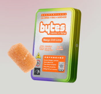 A rectangular metal tin labeled "bytes Powered by torus Mango Chili Lime" with a single sugar-coated gummy placed beside it, shown against a light gradient background.