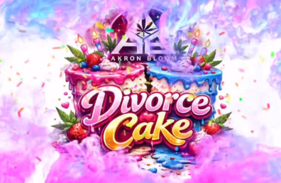 A colorful image shows a split cake with pink and blue icing, candles, fruit, and leaves. The words "Divorce Cake" are written boldly in front, with "Akron Bloom" and a logo above, surrounded by pink and purple smoke.