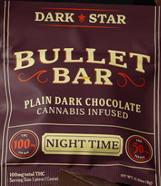 A close-up of a "Bullet Bar" chocolate wrapper labeled "Dark Star," featuring plain dark chocolate infused with cannabis. The packaging indicates 100 mg THC per bar and 50 mg CBD, intended for nighttime use.
