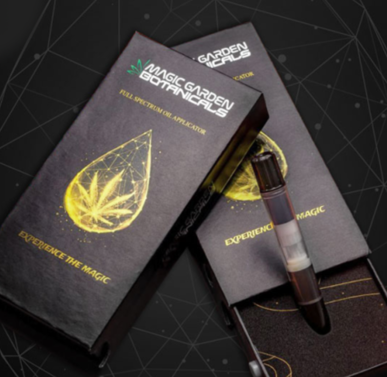 Two black boxes labeled "Magic Garden Botanicals" with a golden cannabis leaf inside a droplet graphic. One box is open, showing a vape pen inside. The slogan "Experience the Magic" is printed on the boxes.