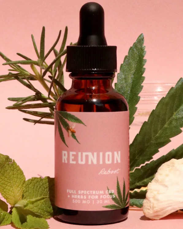 A brown dropper bottle labeled "Reunion" sits beside fresh herbs, suggesting Cannabis Delivery vibes.
