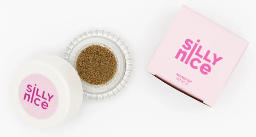 A "Silly Nice" jar and box display brown, sand-like substance on a clean white background.