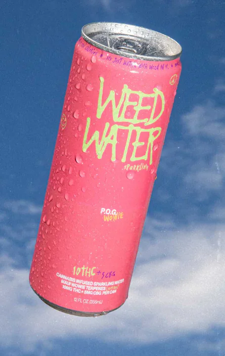 A pink Weed Water can with water droplets floats against a blue sky and clouds in this image.