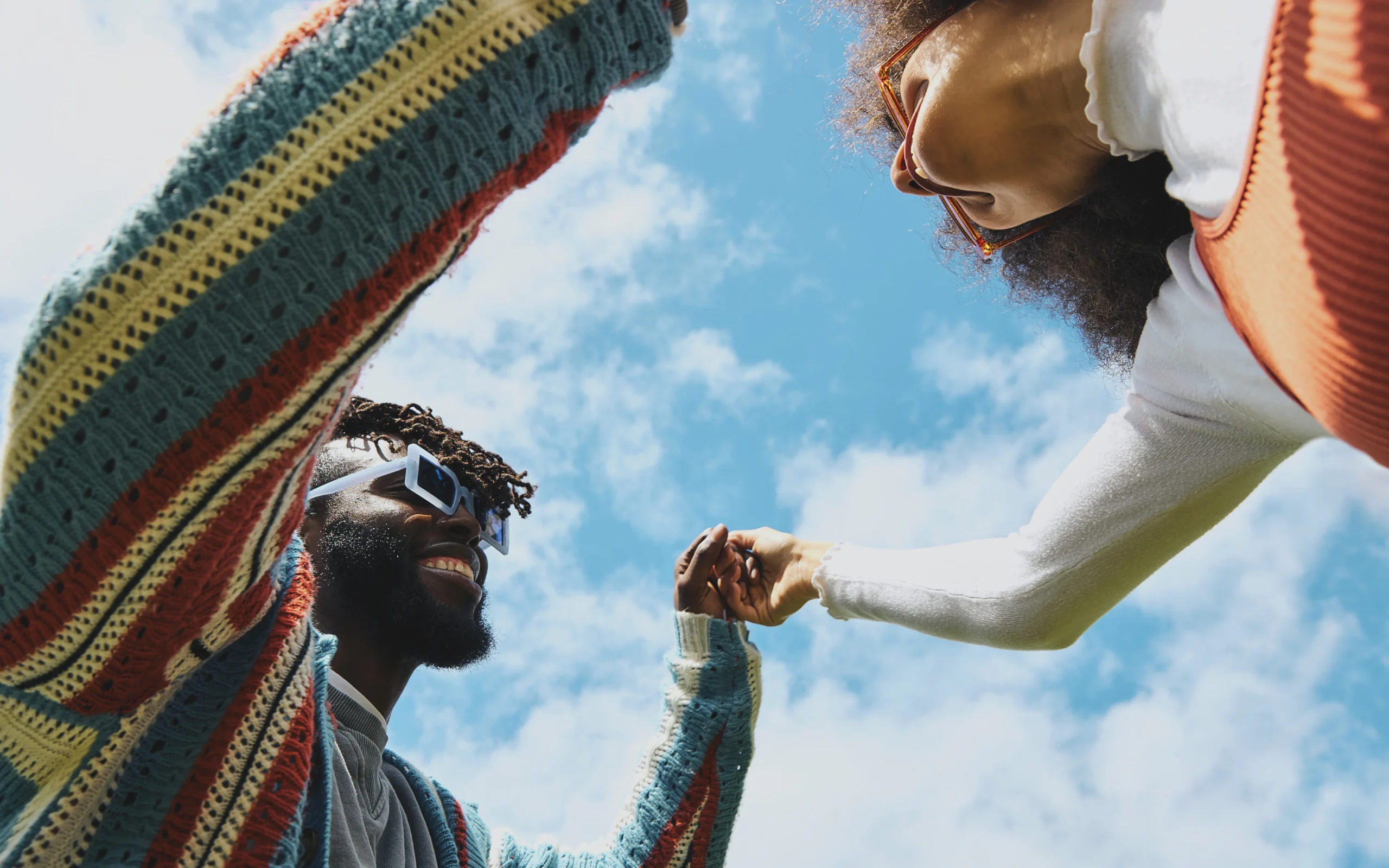 Two people joining hands against a blue sky, Wyld lifestyle photo